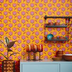 an orange wallpaper with pink and purple flowers on it, next to a gray cabinet