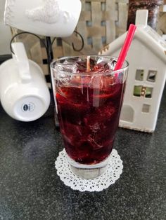 a glass filled with red liquid sitting on top of a counter next to a blender