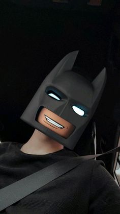 a man wearing a batman mask with glowing eyes sitting in the back seat of a car