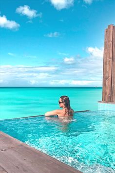 a woman sitting in the middle of a swimming pool next to an open air bathtub