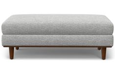 a grey ottoman with wooden legs on a white background