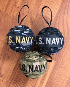 three ball ornaments with us navy and u s navy written on them sitting on a wooden floor