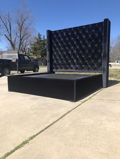 a large black bed sitting on top of a sidewalk