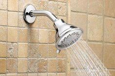 a shower head with the water running from it's spout in front of a brick wall