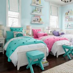 two beds in a room with blue walls and white trim, one has pink and green bedding