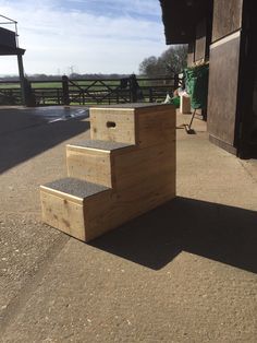 a set of wooden steps sitting on top of a dirt field next to a building