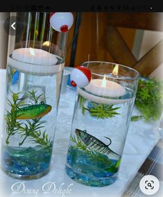 two glass vases filled with water and lit candles