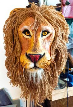 a lion mask sitting on top of a wooden table next to a shelf filled with other items