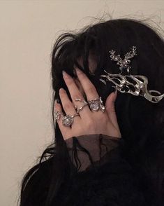 a close up of a person with rings on their fingers and wearing a head piece