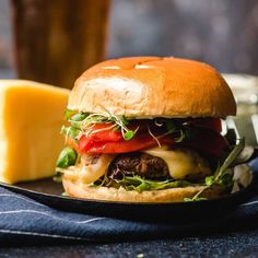 a cheeseburger with lettuce and tomatoes on a plate next to a glass of beer