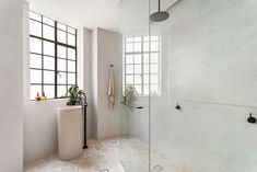 a bathroom with a glass shower door and tiled flooring next to a large window