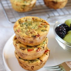 three muffins stacked on top of each other next to a bowl of fruit