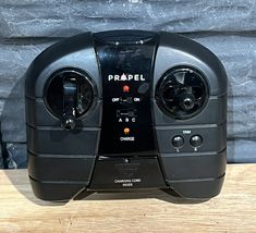 a black radio sitting on top of a wooden table next to a brick wall with the word prael written on it