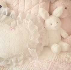 two stuffed animals sitting next to each other on a quilted bedding with white lace