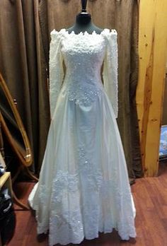 a white wedding dress on display in front of a curtain