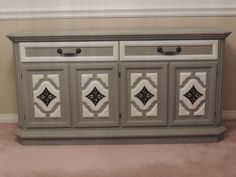 a gray and white dresser with ornate designs on the doors, drawers, and handles