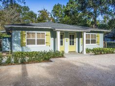 a blue house with yellow shutters and trees in the background