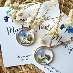 three necklaces with flowers on them sitting next to each other in front of a woven basket