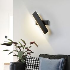 a living room with black couches and pillows on top of the floor next to a white wall