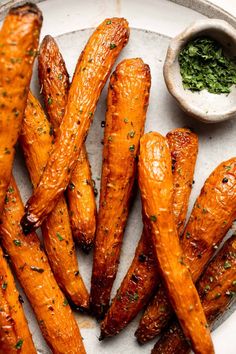 baked sweet potato wedges on a plate with dipping sauce and herbs in the background