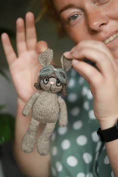 a woman holding up a stuffed animal in front of her face with one hand and the other