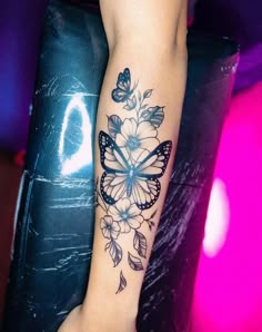 a woman's arm with a butterfly and flowers tattoo on it