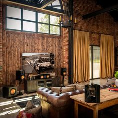 a living room filled with furniture and a large screen tv mounted to the side of a brick wall