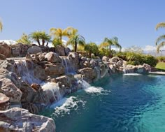 an outdoor pool with waterfall and palm trees