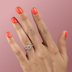 a woman's hand with an orange manicured nail polish and a diamond ring