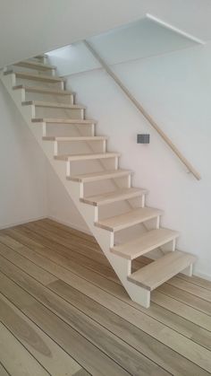 there is a set of stairs in the room with wood flooring and white walls