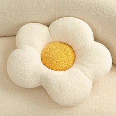 a flower shaped pillow sitting on top of a white couch