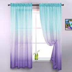 a window with blue and purple ombreed drapes hanging from it's side