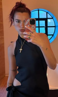 a woman taking a selfie in front of a mirror with a cross on it