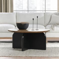 a living room with a white couch and black coffee table in front of a window