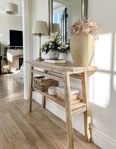 a wooden table sitting in front of a mirror on top of a hard wood floor