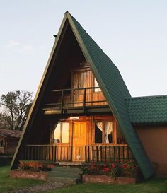 a small house with a green roof and two levels on the front porch is made out of wood