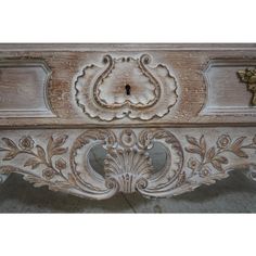 an old wooden table with ornate carvings on the top and bottom, painted in white