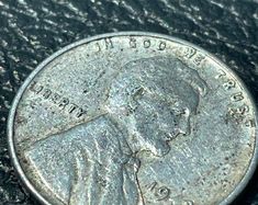 a close up of a coin on a black surface with the image of a man's face