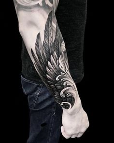 a man with a black and white feather tattoo on his arm