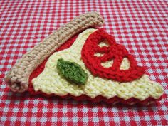 a crocheted slice of pizza on a red and white checkered tablecloth