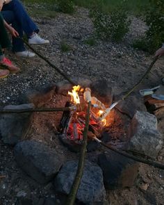 some people sitting around a campfire with sticks