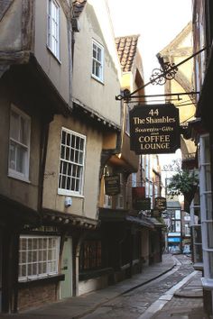 a narrow street with old buildings on both sides and a sign for the starbucks coffee lounge