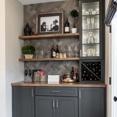 a bar with wine glasses and bottles on the top shelf, next to a door