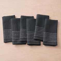 five black towels lined up on a wooden surface