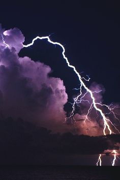 lightning striking over the ocean at night time