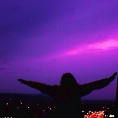 a woman standing on top of a roof with her arms spread wide in the air