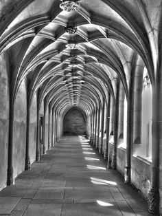 black and white photograph of an arched walkway with sunlight coming through the arches on both sides