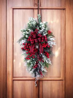 a red and white christmas wreath hanging on a wooden door