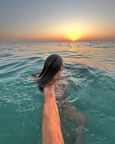 a woman swimming in the ocean at sunset