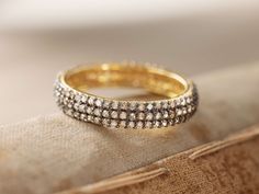 two rows of diamonds are on top of a cushioned surface, and the ring is in yellow gold